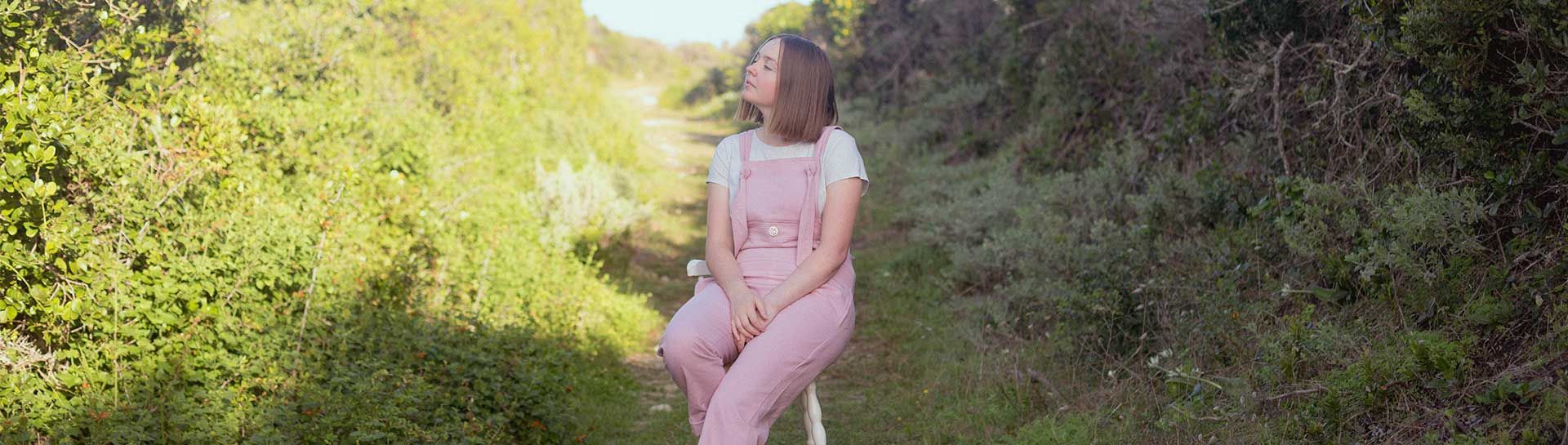 Alina Barnett sitting on a chair on the road around the short there are many plants